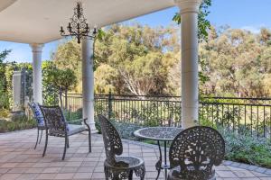 een patio met een tafel en stoelen en een hek bij WOOD14 - River Suite in Perth