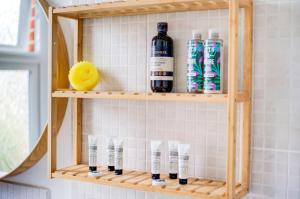 a wooden shelf with bottles and glasses in a bathroom at GuestReady - Harrow Delight near Recreation Ground in London