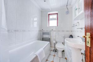 een badkamer met een bad, een toilet en een wastafel bij GuestReady - Bright Terrace House in Maida Hill in Londen