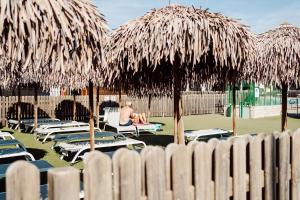a man sitting in a chair under some straw umbrellas at Camping Del Sole Village in Iseo