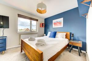 a bedroom with a large bed and a blue wall at GuestReady - Pacific West Coast in Canada Water in London