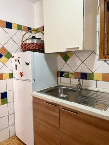 a kitchen with a white refrigerator and a sink at NURAS - Casa Gea in Stintino