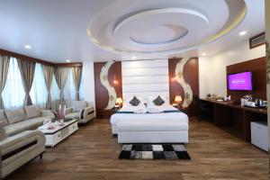 Hotel Sidh Vedantha في باتنا: غرفة بسرير واريكة وتلفزيون