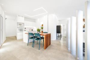 cocina blanca con mesa de madera y sillas azules en La Garita SAL & ARENA, en La Garita