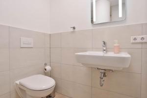 biała łazienka z toaletą i umywalką w obiekcie Apartments in the city center I private parking I home2share w Dortmundzie