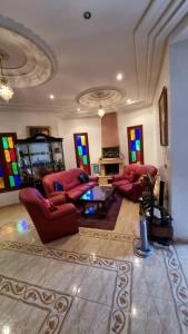 un soggiorno con mobili rossi e vetrate istoriate di Villa with riad style a Fes