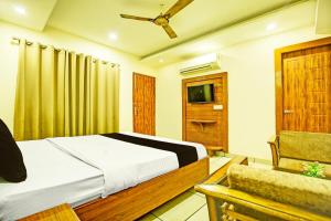 OYO Hotel Grand Signia في Zirakpur: غرفة نوم بسرير وكرسي وتلفزيون