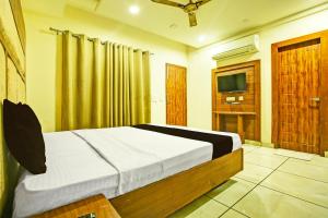 OYO Hotel Grand Signia في Zirakpur: غرفة نوم بسرير وتلفزيون بشاشة مسطحة