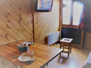 a wooden table with plates and a television on a wall at Studio cosy en front de neige à Risoul 1850, accès direct aux pistes et commodités, 2 couchages - FR-1-330-493 in Risoul
