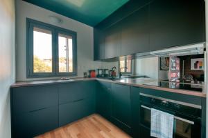 una cocina con armarios de color azul oscuro y una ventana en GuestReady - Apt près du Parc de la Tête d'Or en Lyon
