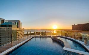 a pool on the roof of a building with the sunset at Intercity Porto Alegre Praia de Belas in Porto Alegre