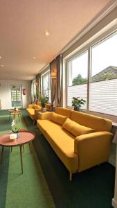 a living room with couches and tables and windows at WannerHus Hotel in Gr&ouml;mitz