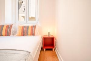 una cama con una mesita de noche roja junto a una ventana en GuestReady - Captain's residence R/C near Alfama, en Lisboa
