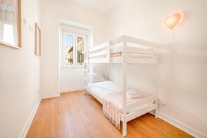 Litera blanca en habitación con suelo de madera en GuestReady - Captain's residence R/C near Alfama, en Lisboa