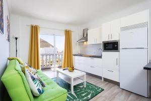 Una sala de estar con un sofá verde y una cocina. en Home2Book Charming Apt Mountain Views Los Silos, en Los Silos