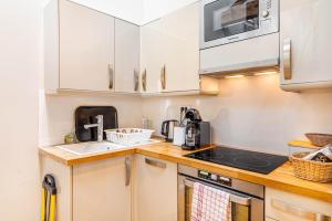 une cuisine avec des armoires blanches et un four à plaques de cuisson dans l'établissement GuestReady - Comfortable getaway near Paris, à Boulogne-Billancourt