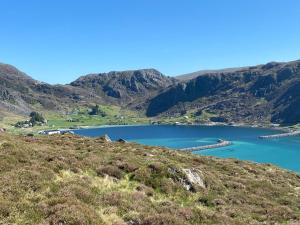 a lake on a hill with mountains in the background at Honey bay cottage in Stadlandet