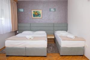 two beds in a hotel room with towels on them at Motel New Sanatron in Bosanski Novi