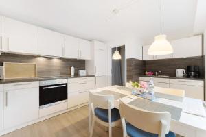 a kitchen with white cabinets and a table with chairs at Ferienwohnung Angeln in Ulstrupfeld
