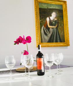 eine Flasche Wein und Gläser auf dem Tisch mit einem Gemälde in der Unterkunft Chic in Fiumicino