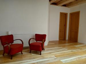 two red chairs in an empty room with wooden floors at Spillenberg House Main Property 2024 in Levoča