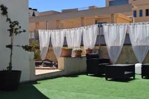 eine Terrasse mit weißen Vorhängen und Stühlen auf einem Gebäude in der Unterkunft VESPRI 15 apartments in Trapani