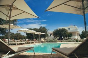 モノーポリにあるVILLA AL MARE sea, relax & wellnessのラウンジチェアとパラソル付きのスイミングプール