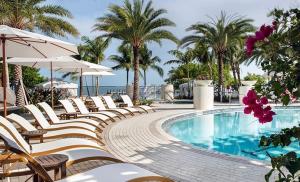a row of chairs and a swimming pool with palm trees at Endless Summer 42 in Key Largo
