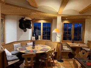a dining room with a table and chairs and a room with a couch at Hôtel Magrappé in Veysonnaz