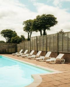 una fila di sedie a sdraio accanto alla piscina di Hot Tub Lodge Cornwall - Meadow Lakes Holiday Park a St Austell Altre 5 foto