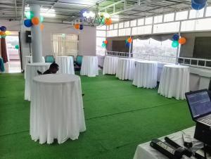 Habitación con mesas blancas y alfombra verde. en Empolos Hotel Nakuru, en Nakuru