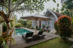 a patio with two chairs and an umbrella next to a pool at Wage cottage in Nusa Penida