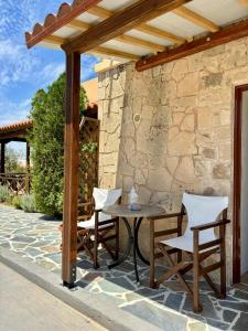 un patio con mesa y sillas bajo una pérgola en Lily's studio en Vathí