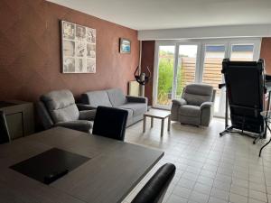een woonkamer met een bank, stoelen en een tafel bij Camping De Collignon in Cherbourg en Cotentin