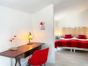 a bedroom with a desk and a bed with red sheets at Chemin des Ormeaux in Ennezat