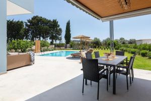 um pátio com uma mesa e cadeiras e uma piscina em Villa Ethria Rhodes em Afantou