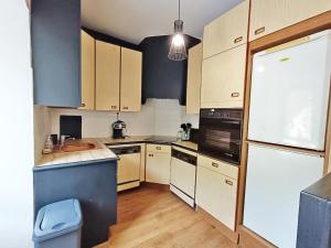 a kitchen with wooden cabinets and a white refrigerator at Le Télécab', T5, wifi, cave, ascenseur, 8 personnes in Luchon +23 photos