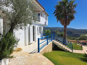 a white house with a blue staircase and a palm tree at Villa Emilios in Lakhanádha