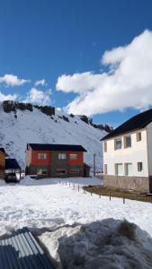 a snow covered yard with a building and a mountain at CUNCUMEN Caviahue in Caviahue