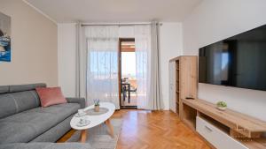 Una sala de estar con un sofá y un televisor. en Modern Apartment Ana, en Malinska