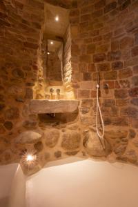 Baño de piedra con lavabo y espejo en The Monastery - Unique Vacation Home, en Monteprandone