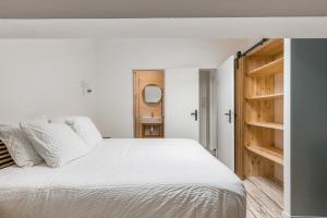 - une chambre avec un lit blanc et des étagères en bois dans l'établissement COZY HAVEN Appart. industriel neuf proximité hôpital Bellevue, à Saint-Étienne