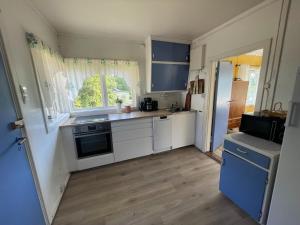 uma pequena cozinha com armários brancos e uma janela em Furuly by Norgesbooking - cabin 20 meters from the beach em Hyggen