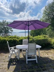 uma mesa e duas cadeiras com um guarda-chuva roxo em Furuly by Norgesbooking - cabin 20 meters from the beach em Hyggen