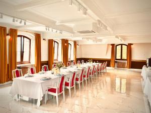 ブィドゴシュチュにあるHotel Pałac w Myślęcinkuの白いテーブルと赤い椅子が備わる宴会場