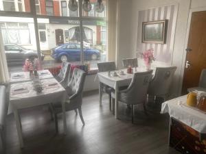 a dining room with white tables and chairs and a window at The Cosy Nook in Blackpool