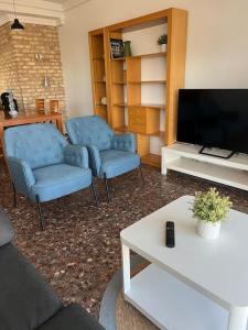 Sala de estar con 2 sillas azules y TV en Playa Malvarrosa House en Valencia