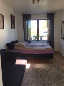 een bed in een kamer met een raam en een bank bij Motel Villa Søndervang 3 personers værelse in Harndrup