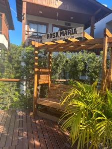 a wooden bench on a deck in front of a house at Pousada Rosa Maria in Praia do Rosa