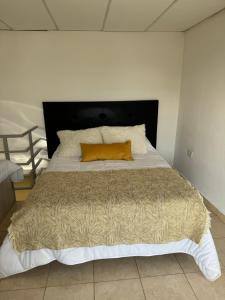 Una cama grande con una almohada naranja. en Aura en General Fernández Oro